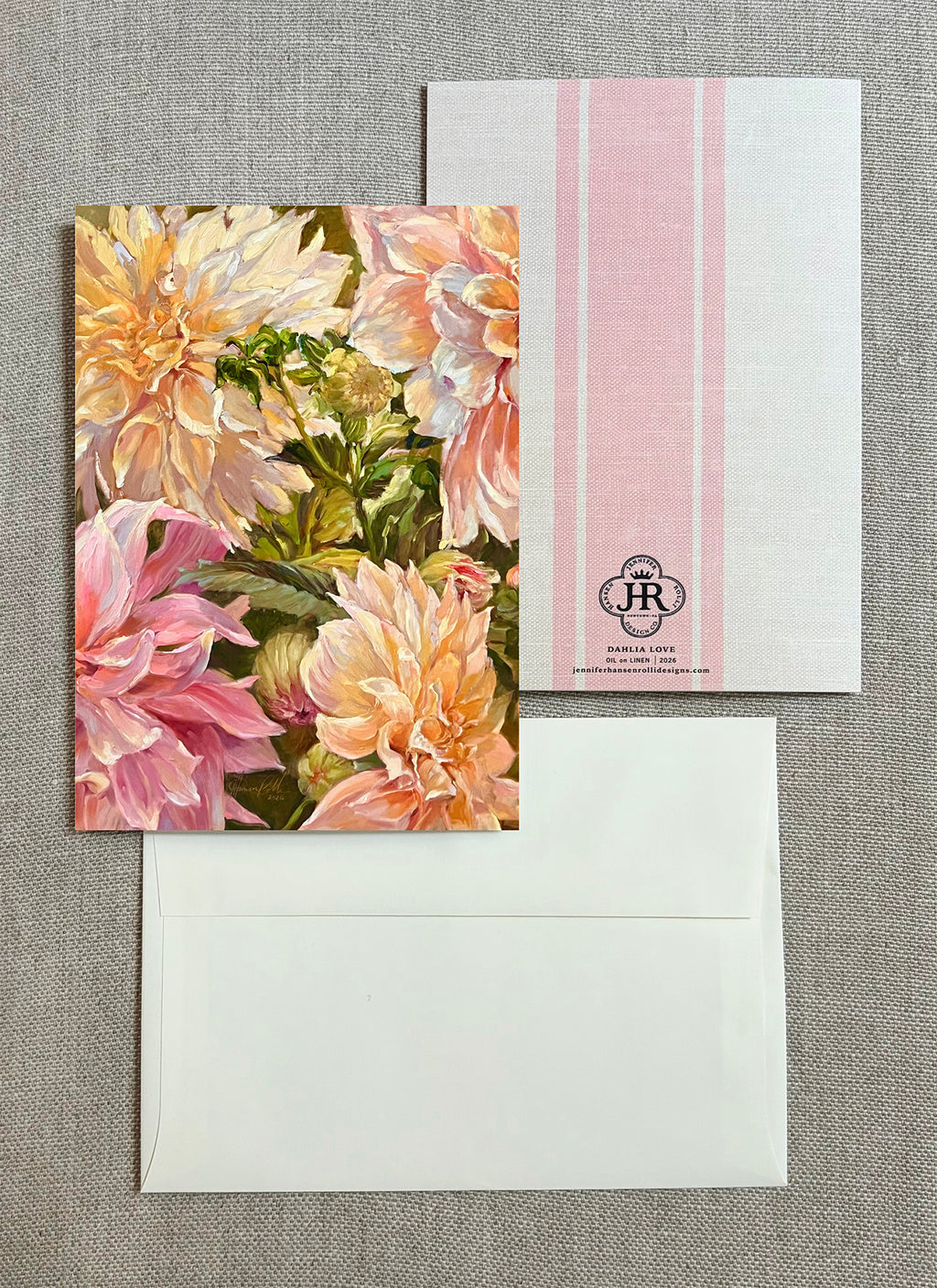 A floral greeting card with large pink and cream flowers, shown with a white envelope and a white postcard featuring pink vertical stripes and a small 'JR' monogram.