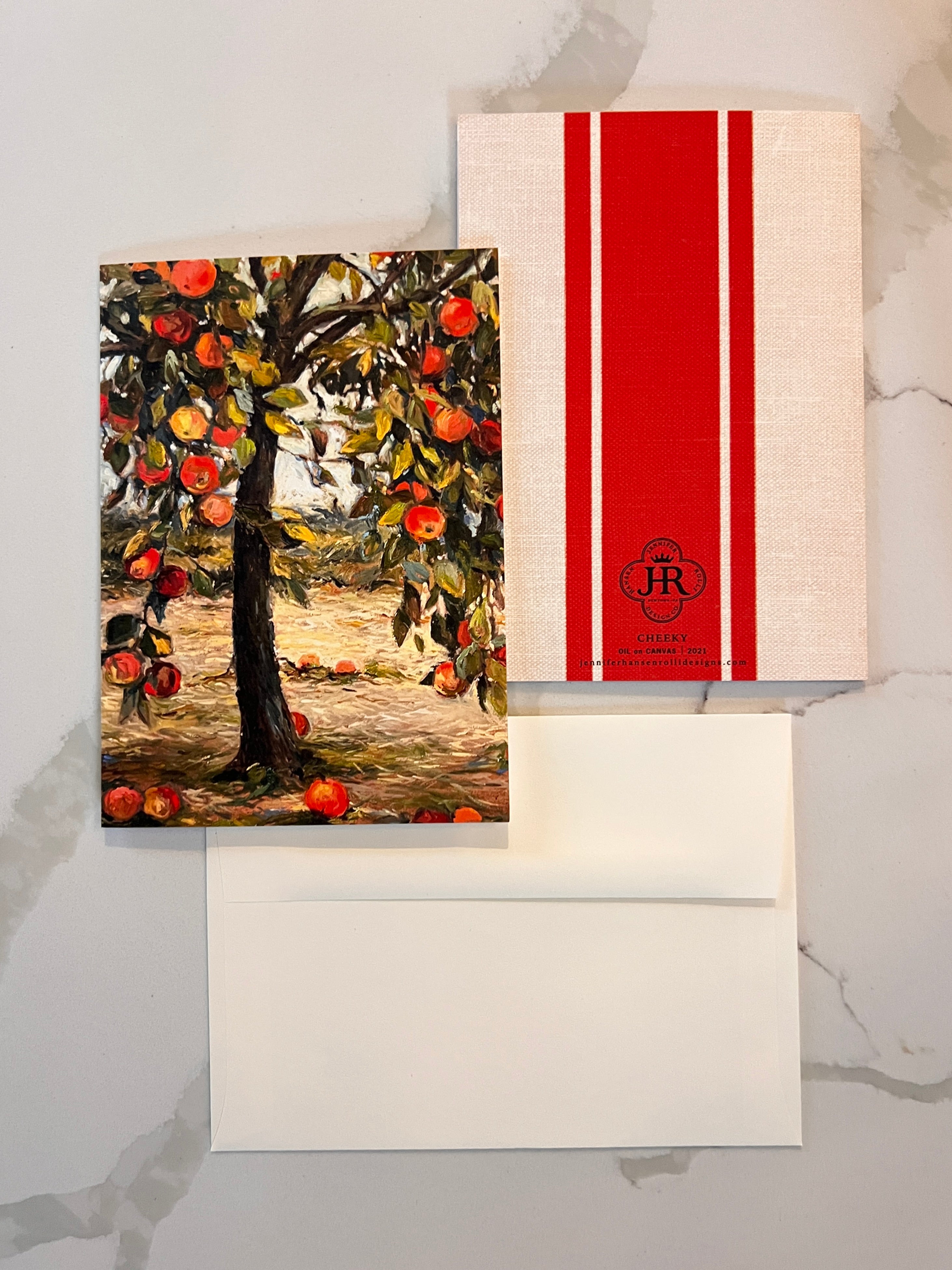 Framed artwork of an apple tree with a red and white striped box on a marble surface