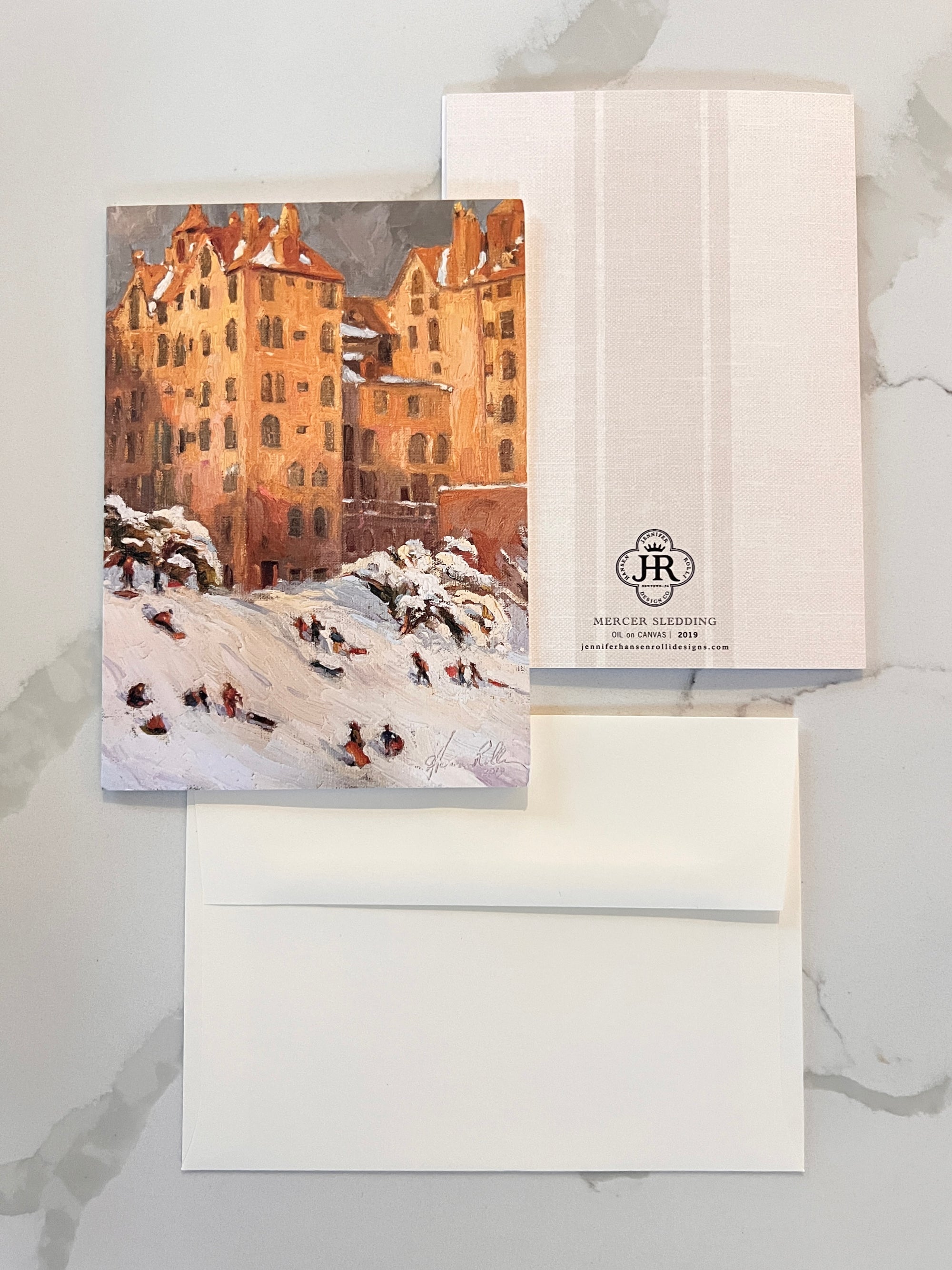 Greeting card with winter scene and envelope on a marble surface