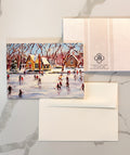 Card with a winter scene of people skating on a pond, featuring a snowy village and trees.