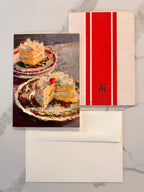 Greeting card with a slice of cake and a red and white striped back side on a marble surface.