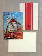 A stationery set laid flat on a textured beige fabric background, including a printed greeting card with an impressionistic red house and blue sky scene, a white envelope with a bold red vertical stripe and a small circular 'JR' logo, and another white envelope below.