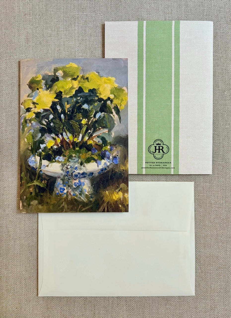 A floral greeting card featuring an impressionist painting of yellow and blue flowers, shown with its matching cream envelope and a white envelope with green vertical stripes and a monogram logo.
