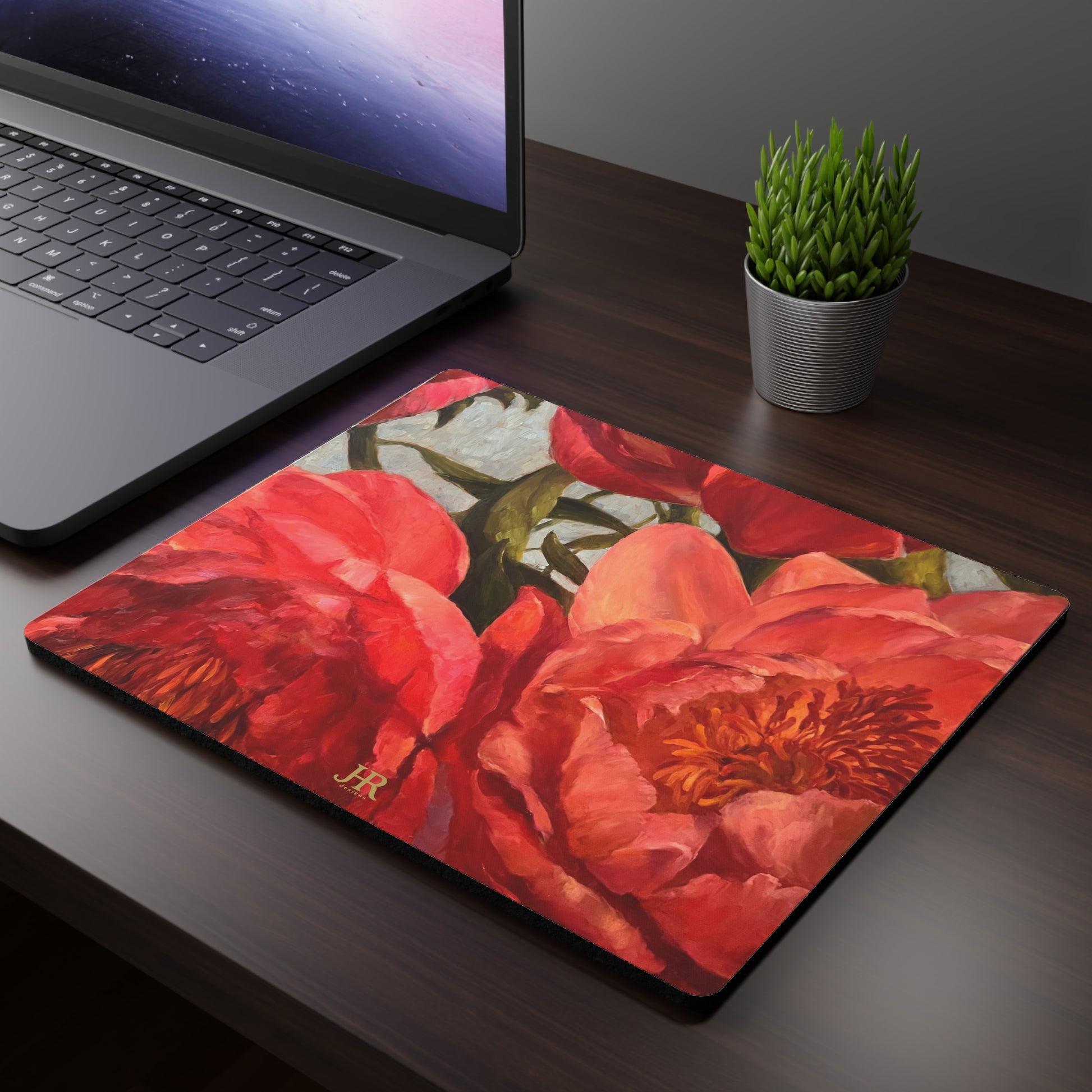 A mousepad on a desk featuring the red peony artwork of artist Jennifer Hansen Rolli.